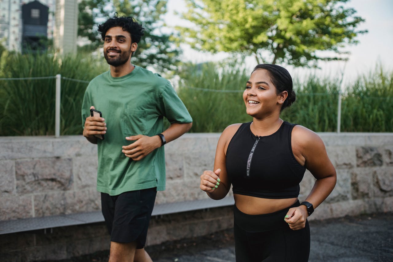 A man and woman jogging outdoors, enjoying a healthy lifestyle on a sunny day.